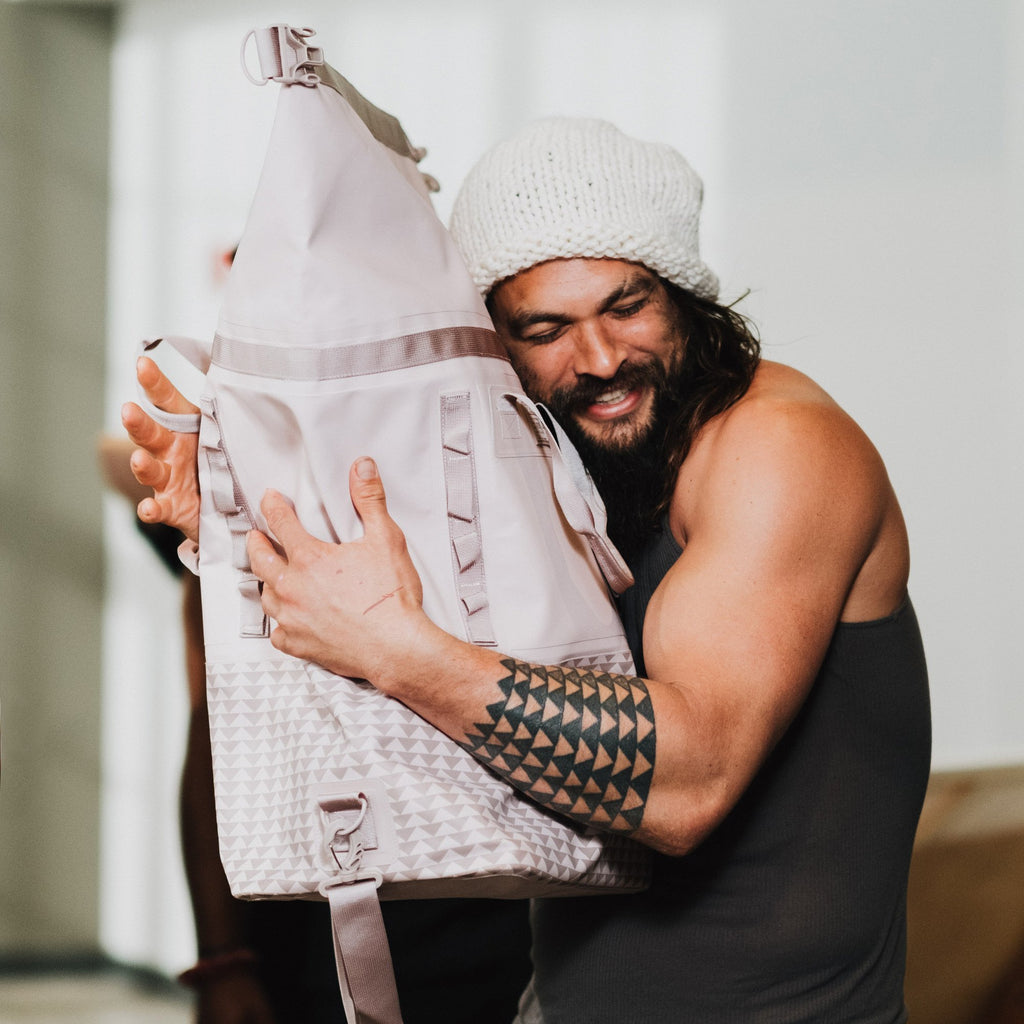 Jason Momoa hugs a dirty pink dirt bag during an inspection of the development samples