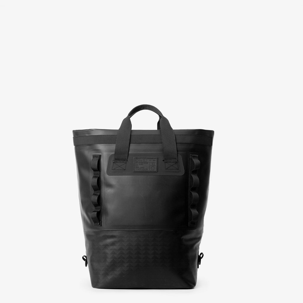 the front of a black 25L so ill x on the roam dirt bag is shown rolled down to be carried as a tote on - a grey background